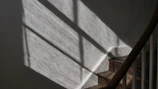 A stairway wall lamp creating dynamic shadows on textured walls, enhancing the staircase ambiance.