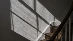A stairway wall lamp creating dynamic shadows on textured walls, enhancing the staircase ambiance.
