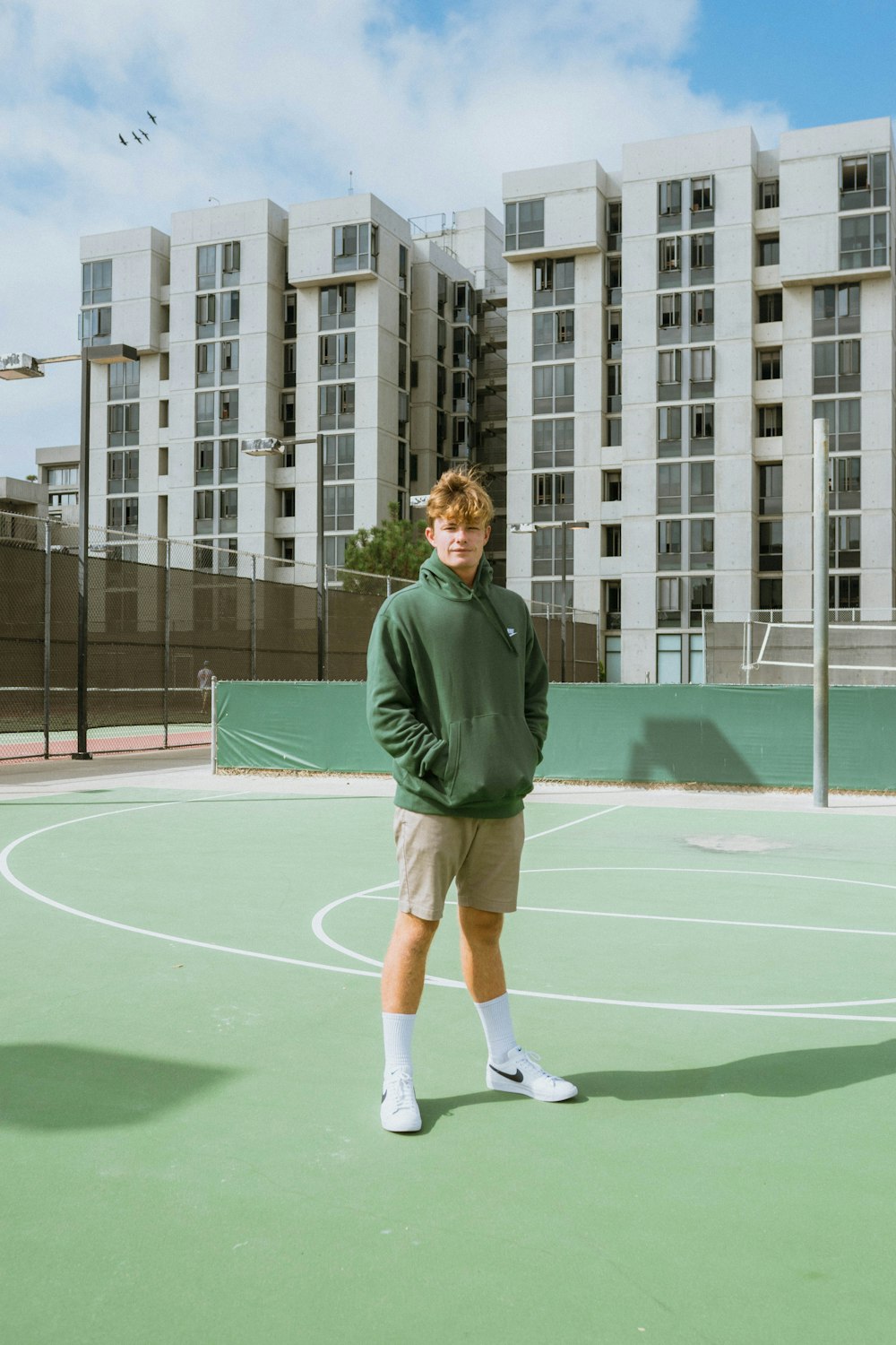 standing man wearing green pullover hoodie inside court