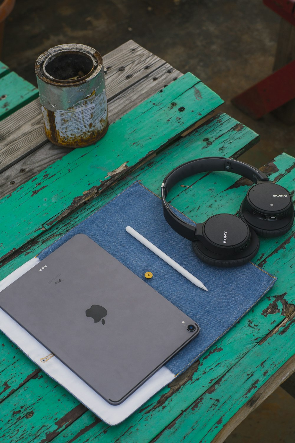 black cordless headphones beside iPad on green table