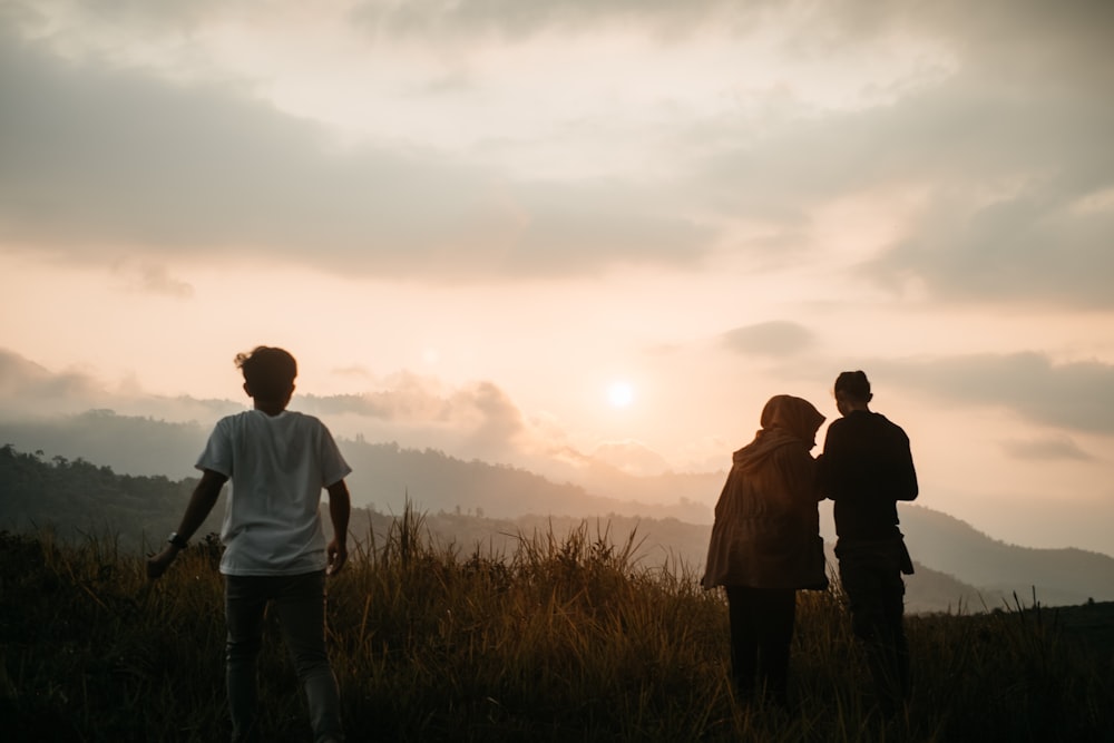 three persons on grass field