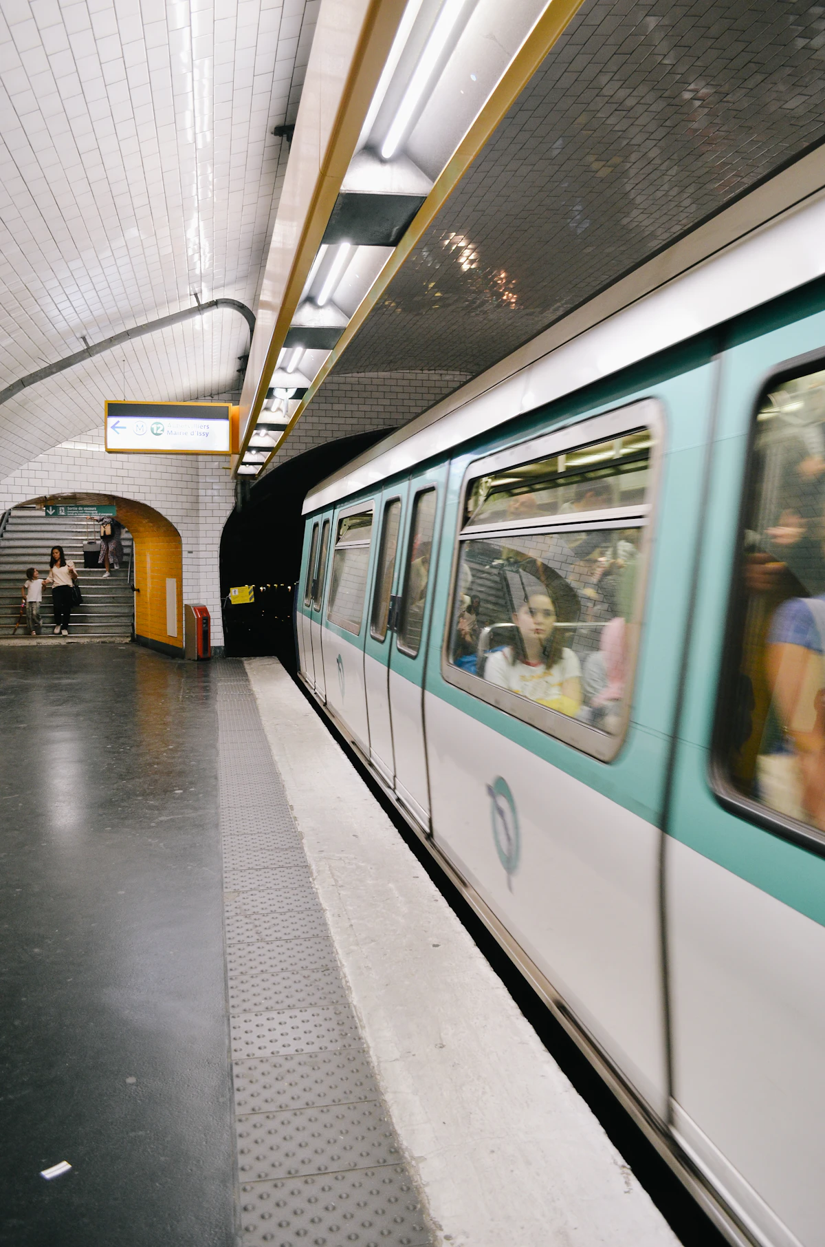 Rame de métro parisien entrant en station souterraine, carrelage blanc caractéristique de la RATP.