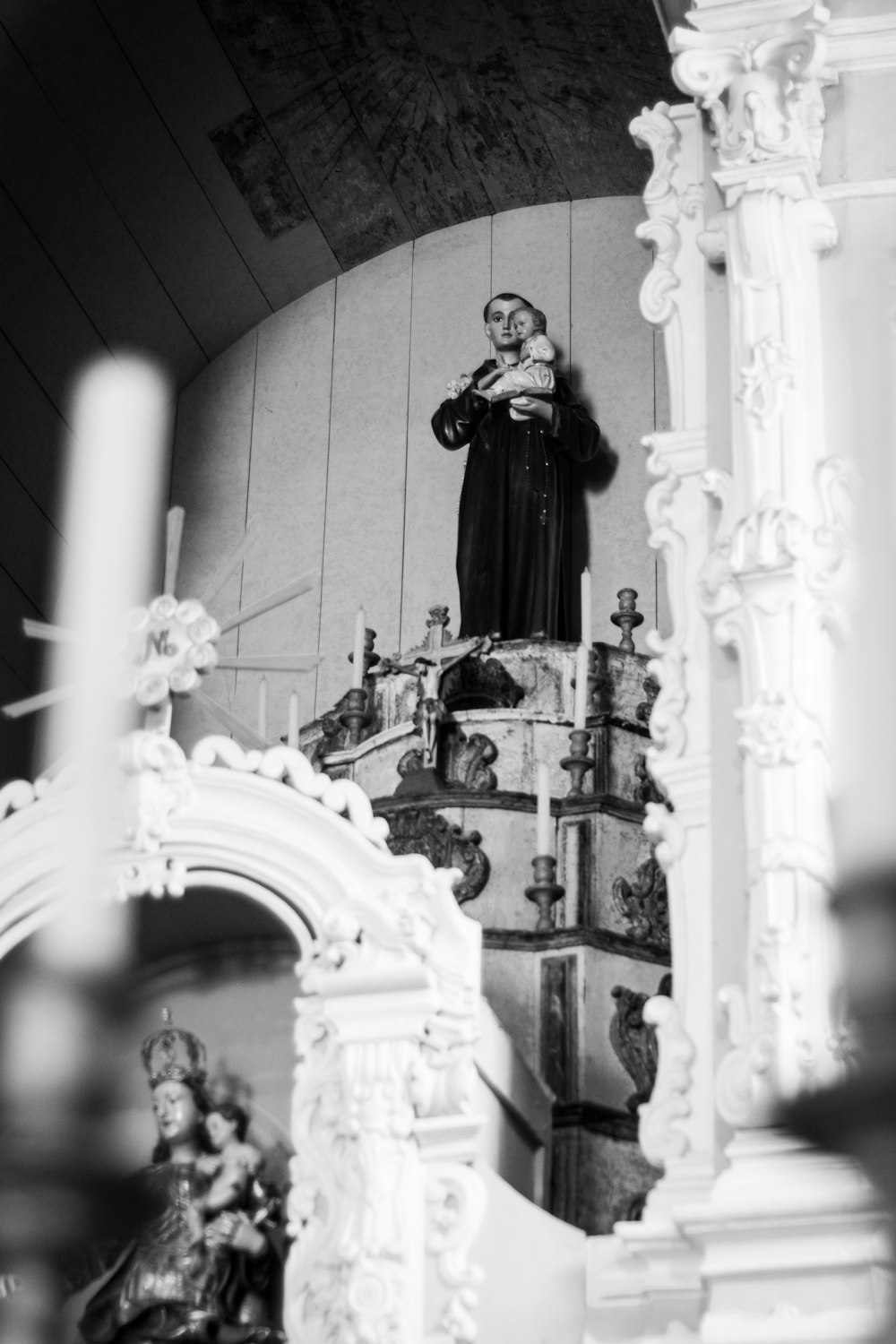 grayscale photography of religious man carrying baby Jesus statue