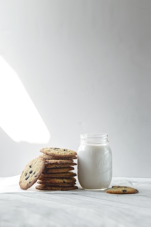 A cozy kitchen scene with a jar of cookies next to a warm cup of milk.