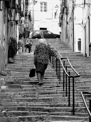 An elderly woman smiling as she uses an easystep assisted device to climb stairs in her home