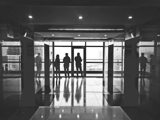 grayscale photography of three person in building