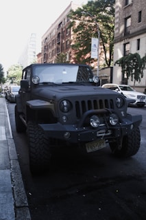 A tow truck loading a 4x4 vehicle in an urban area with buildings in the background