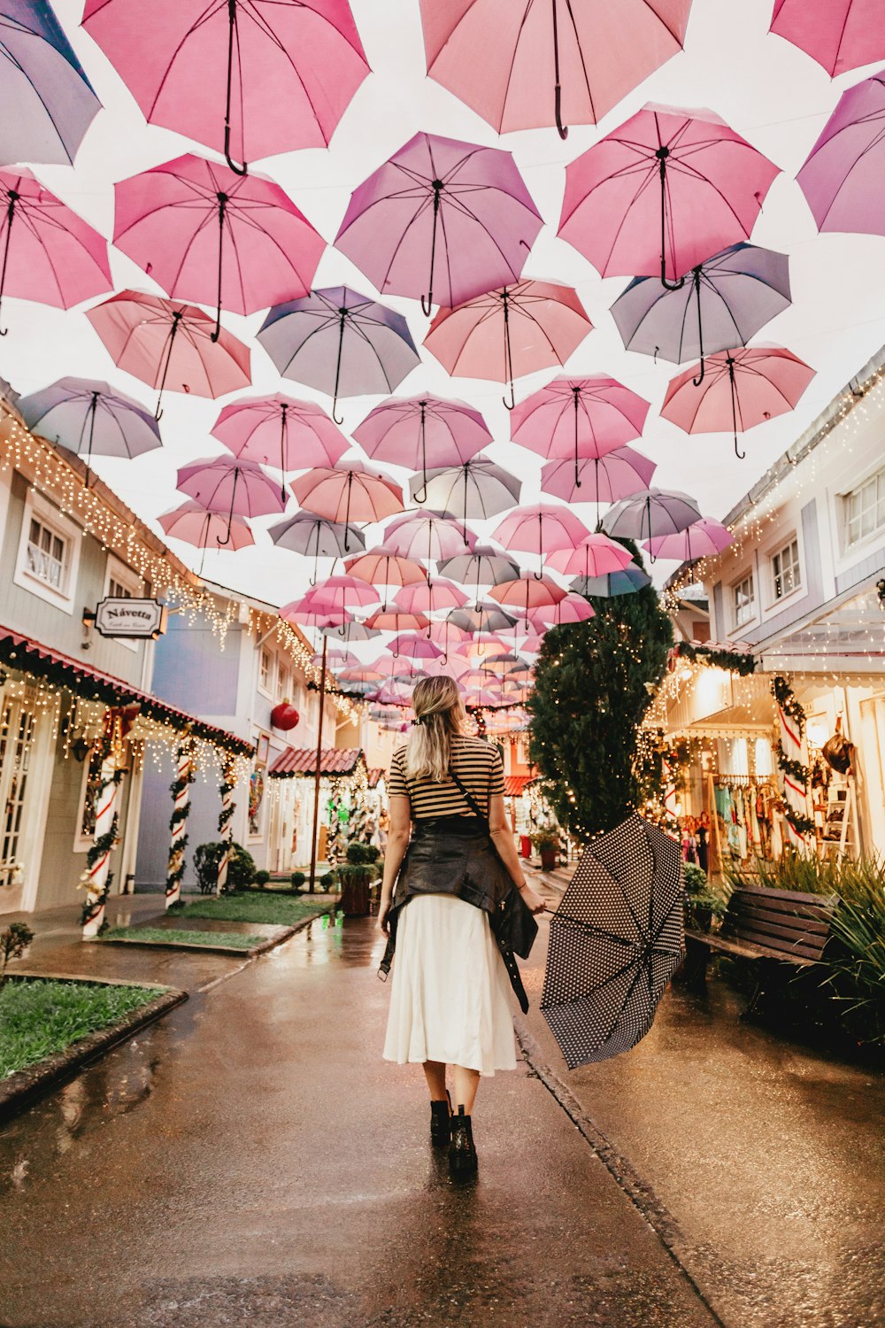 Frau steht unter rosa Regenschirmen