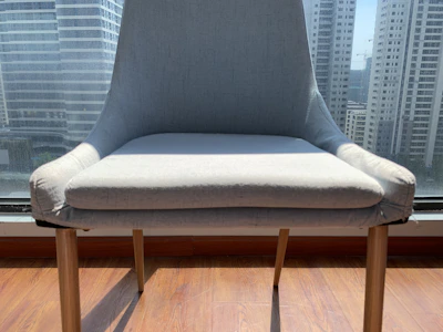 Modern industrial chair with clean lines made of metal and wood, placed near a large window.