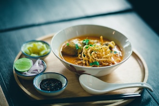 A beautifully plated bowl of pho with fresh herbs and vibrant colors on a wooden table.