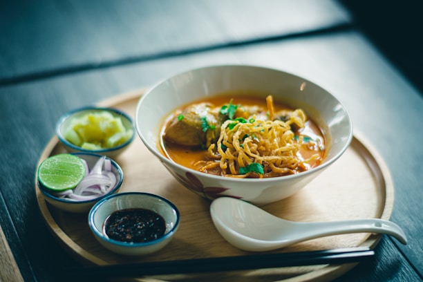 A beautifully plated bowl of pho with fresh herbs and vibrant colors on a wooden table.