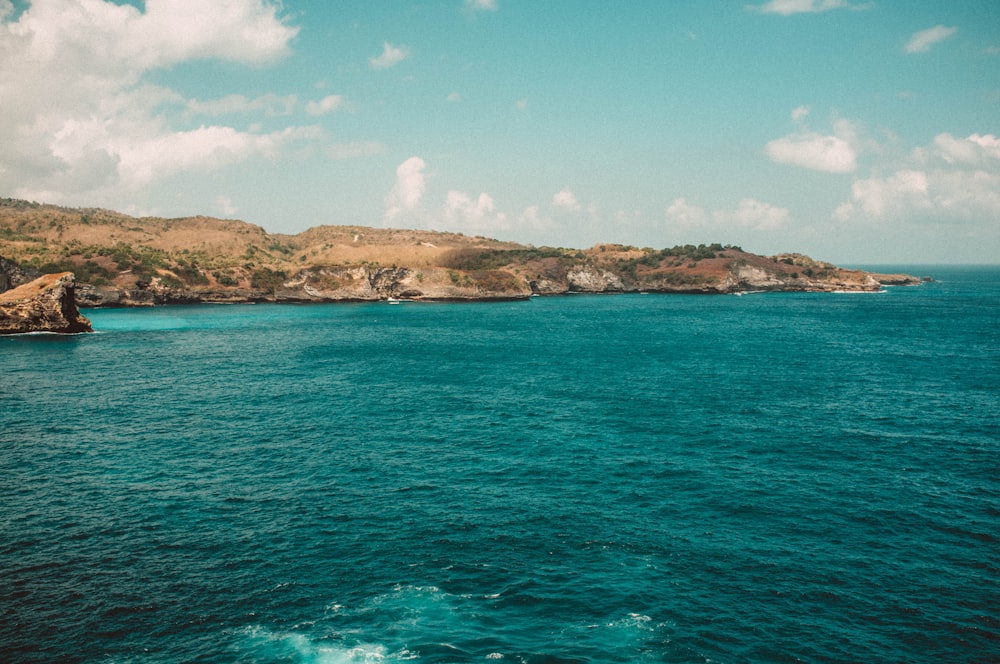 body of water near mountains at daytime