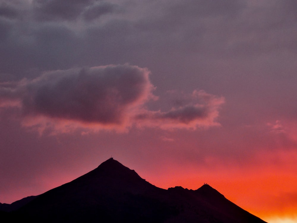 a plane flying over a mountain under a cloudy sky