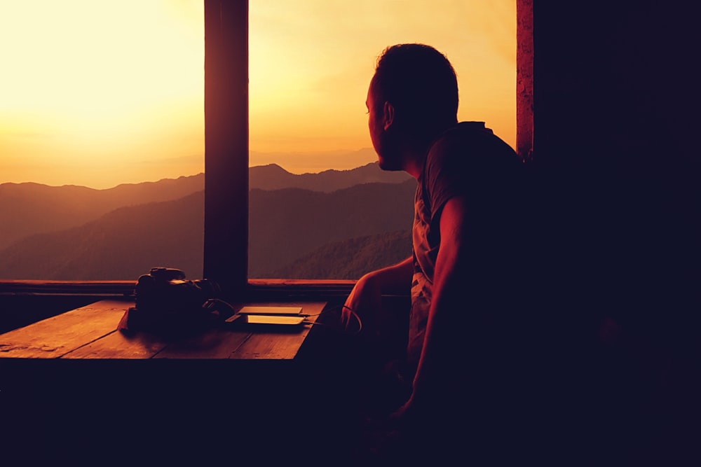 a person sitting at a table looking out a window