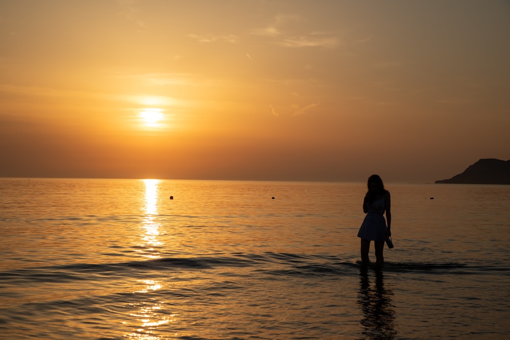 person standing in body of water during golden hour