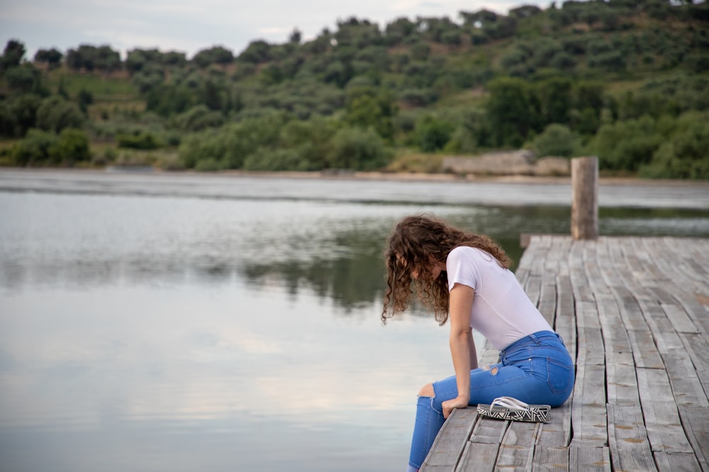 woman sitting on gray wooden dock during daytime