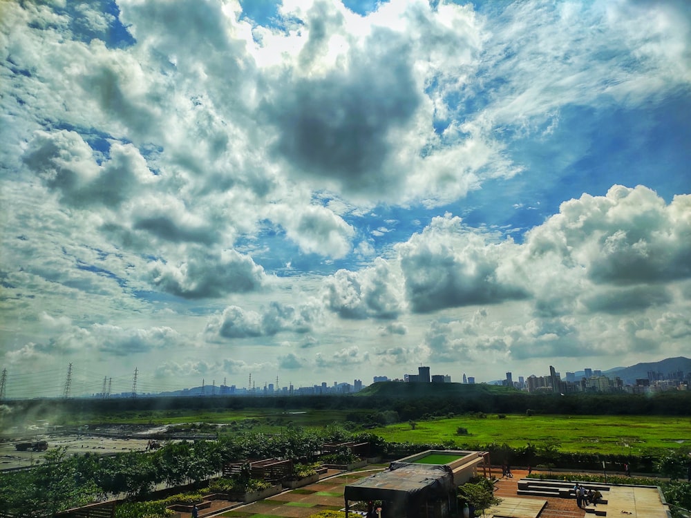 wide view of grassland across city building during cloudy daytime