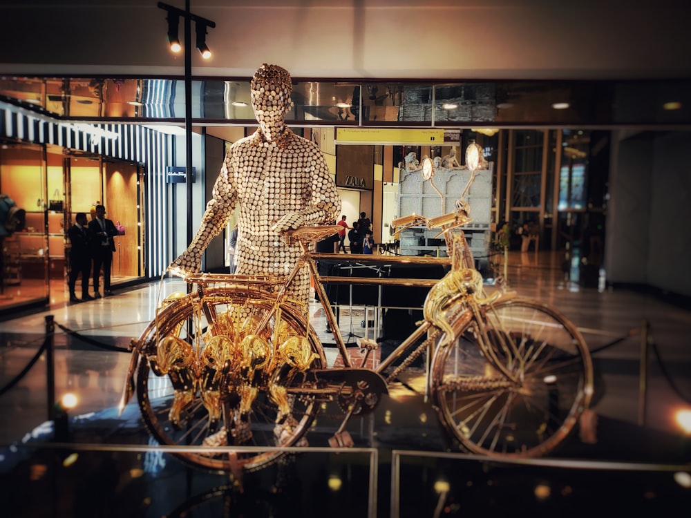 gold-colored statue of man holding bicylce