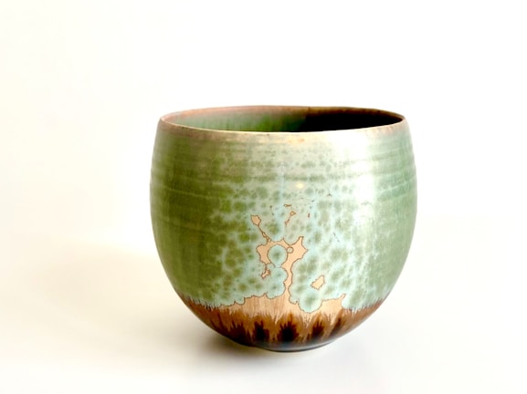 Close-up of a handcrafted ceramic bowl with earthy textures and moss green glaze.