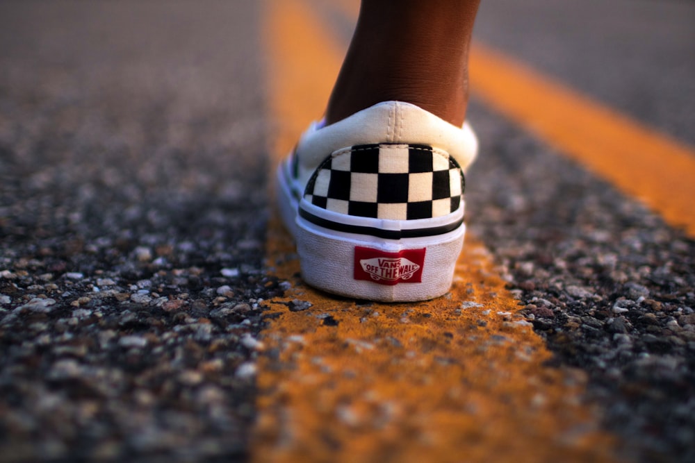 person wearing white and black Vans Off The Walls low-top sneaker