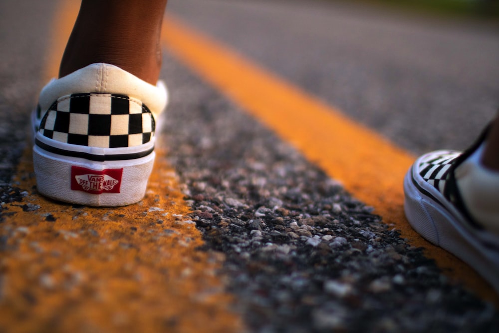 person wearing white-and-black Vans Off The Wall low-top sneakers