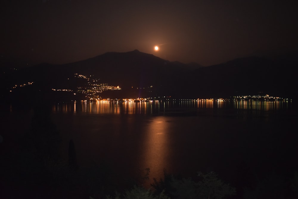 a full moon is seen over a lake at night