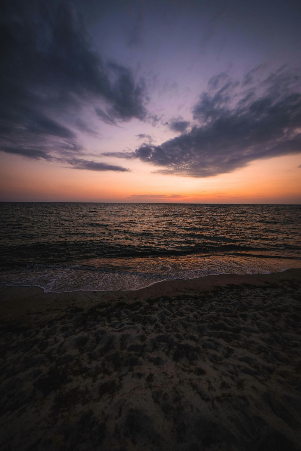 a sunset over the ocean with clouds in the sky