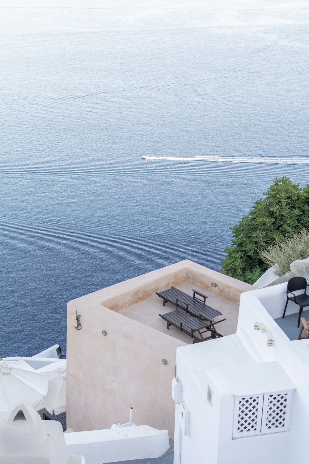 2 black outdoor lounges on building terrace across body of water
