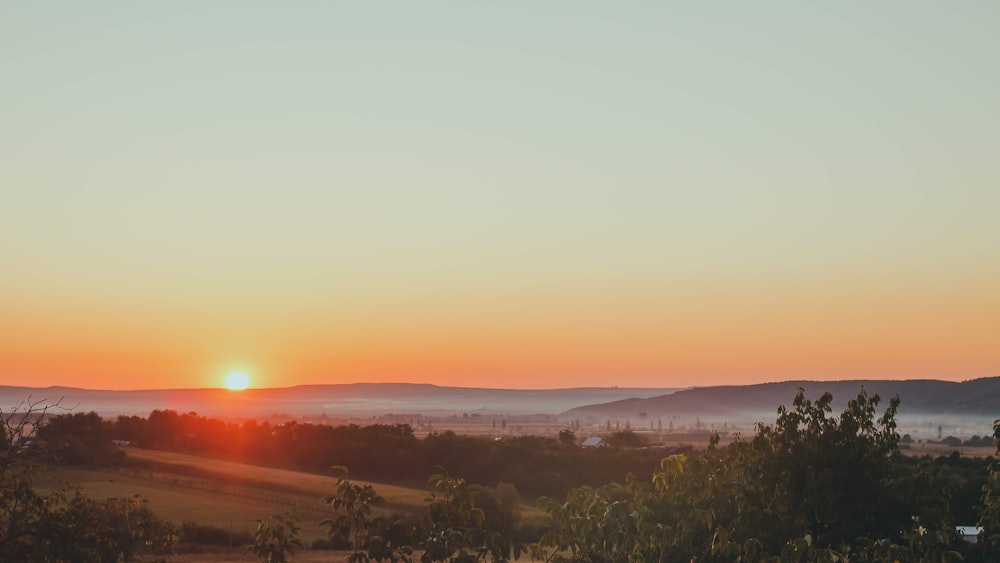 the sun is setting over the mountains in the distance