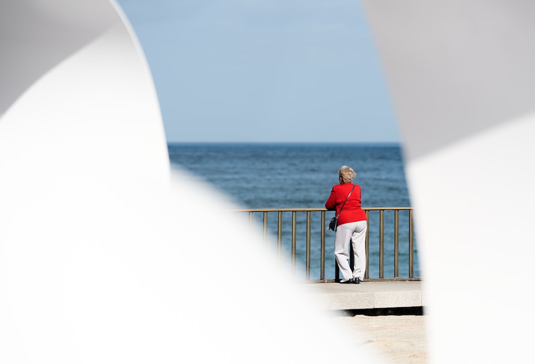 woman in red long-sleeved shirt watching the body of water