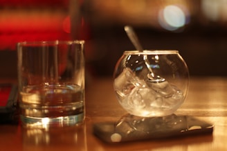 Close-up of a warm wooden table with a saunapearls mold and freshly pressed ice sphere resting beside a steaming sauna bucket.