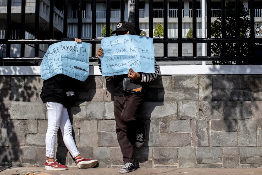 two person holding blue printed signages