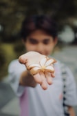 Hands holding a handful of mixed dried fruits against a green leafy background.