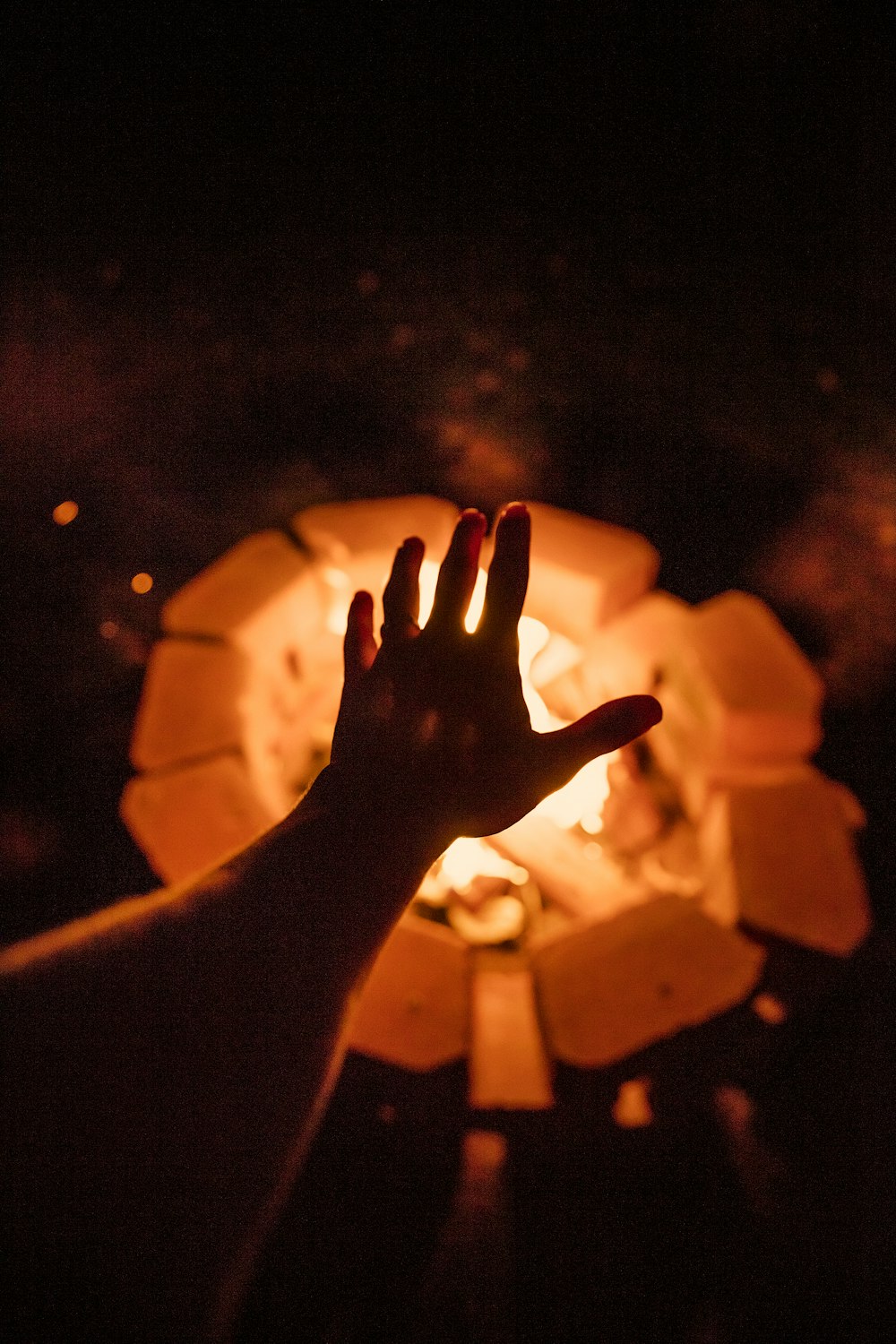 Foto donde se ve una mano calentándose en un fuego de leñ