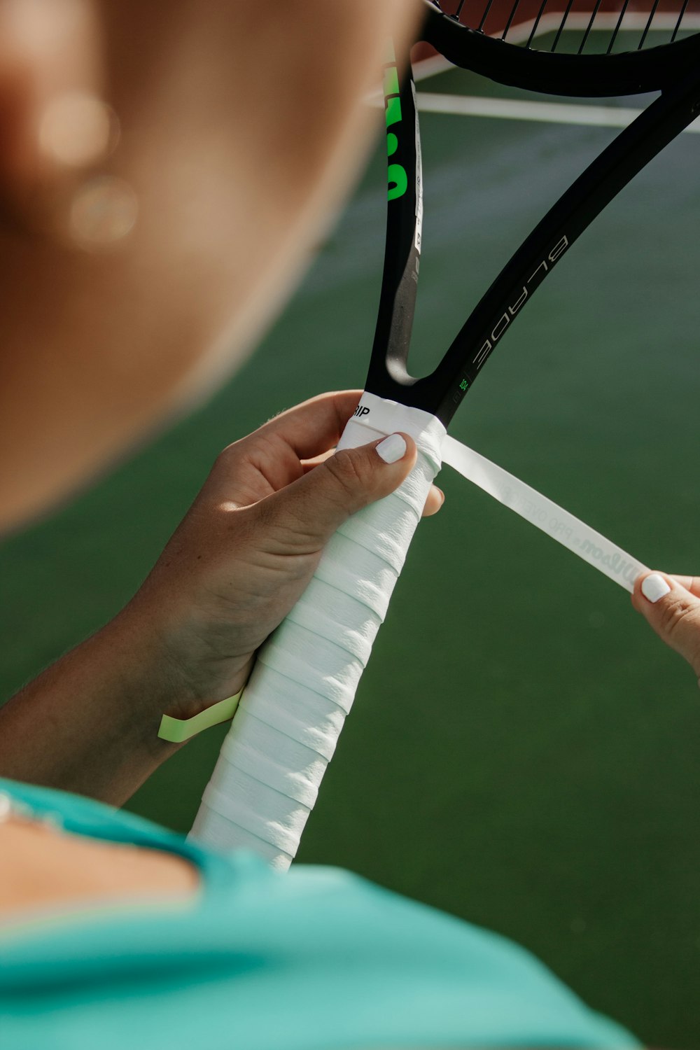 mujer fijando cinta blanca en cohete de tenis