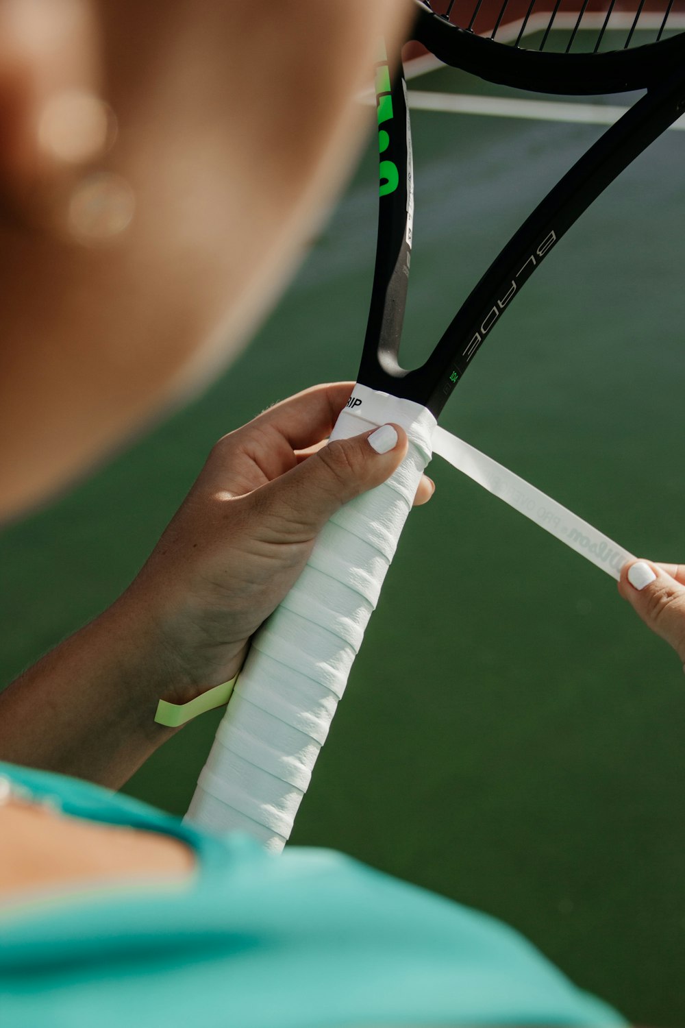 woman fixing white tape on tennis rocket