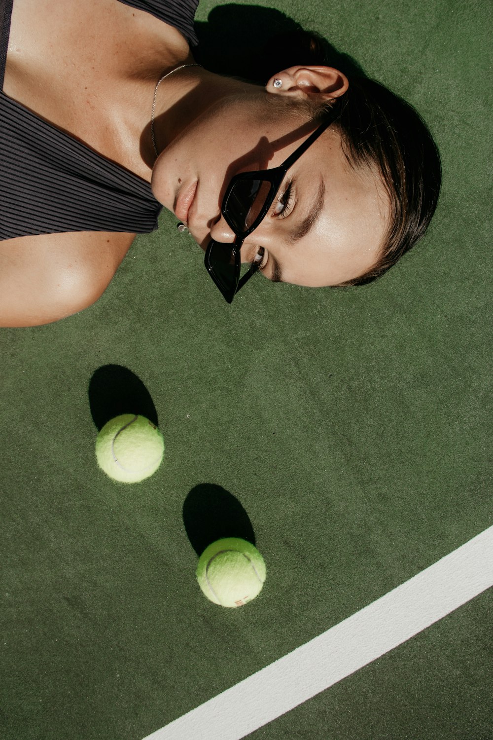 두 개의 녹색 테니스 공 옆에 누워있는 여자