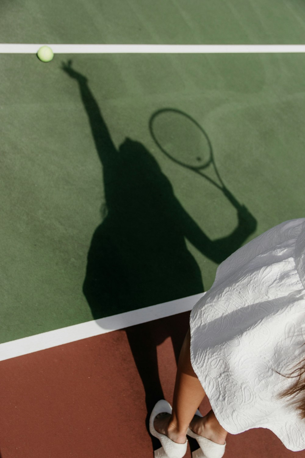 ombre d’une femme jouant au tennis sur le court