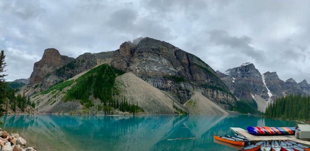 boats docked on lake beside mountain