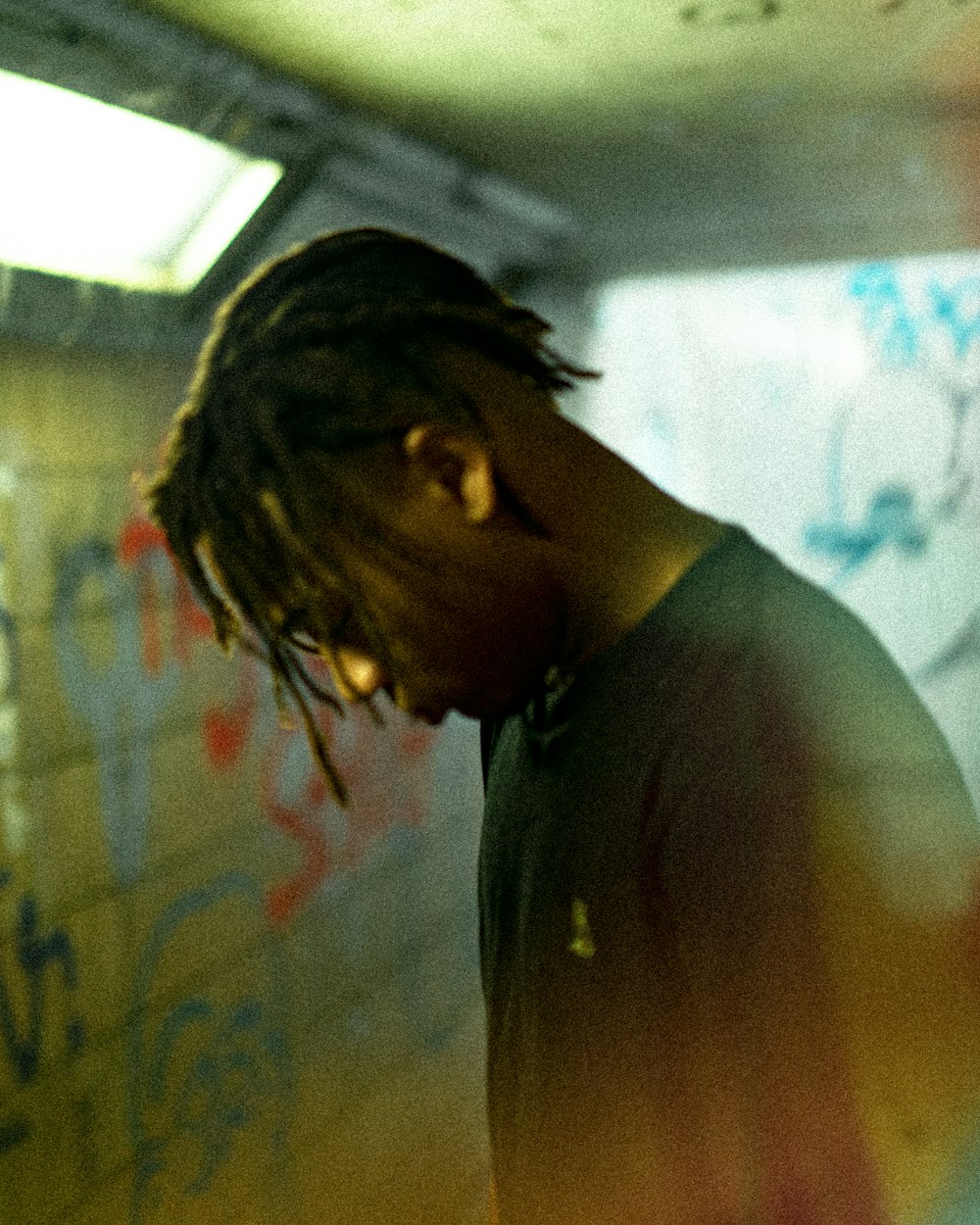 man in black shirt standing front of graffiti wall