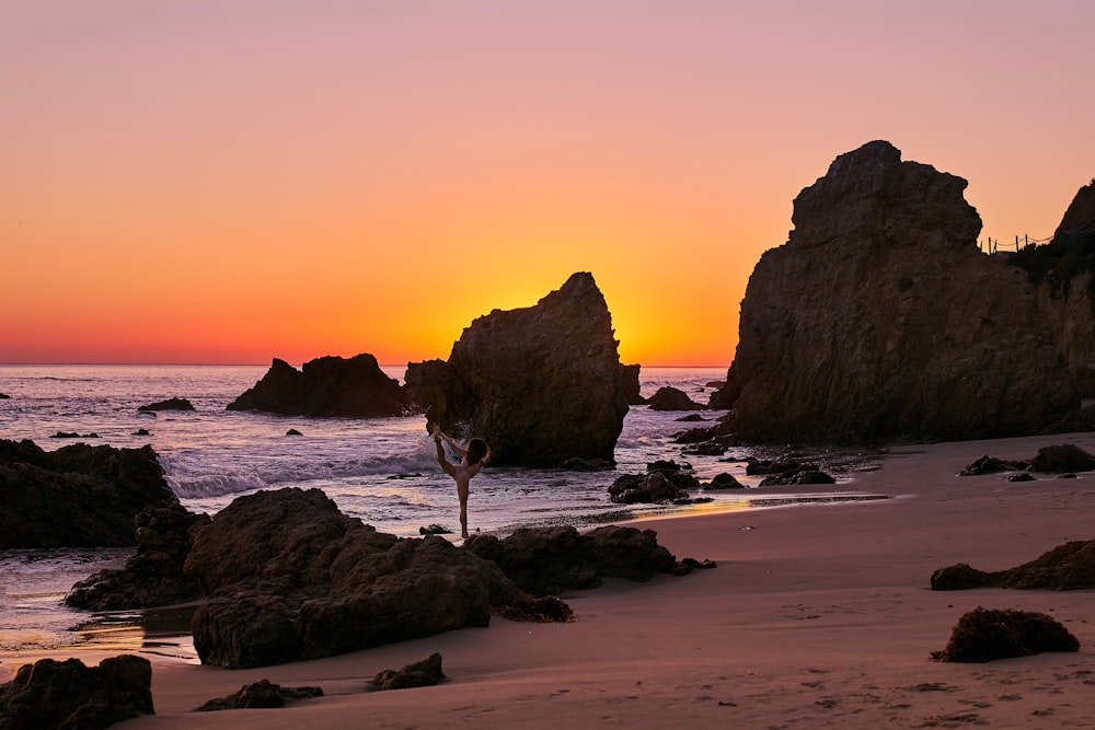 a sunset on a beach with rocks and water