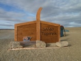 A rustic wooden sign marking the entrance to the desert camp at dusk.
