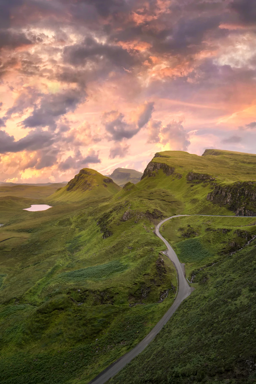 A winding road through green hills on the Isle of Skye at sunset