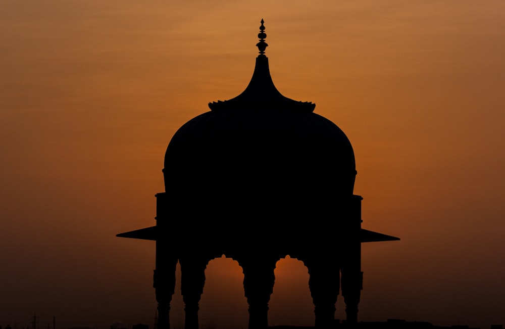 a silhouette of a building against a sunset sky