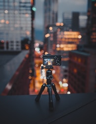 camera on tripod on building roof ledge at the city during night
