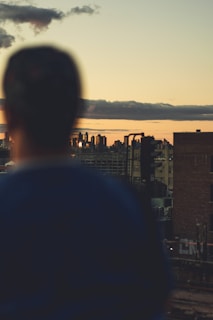 Evening city skyline blurred in the background behind a person dressed in urbanhikes techwear.