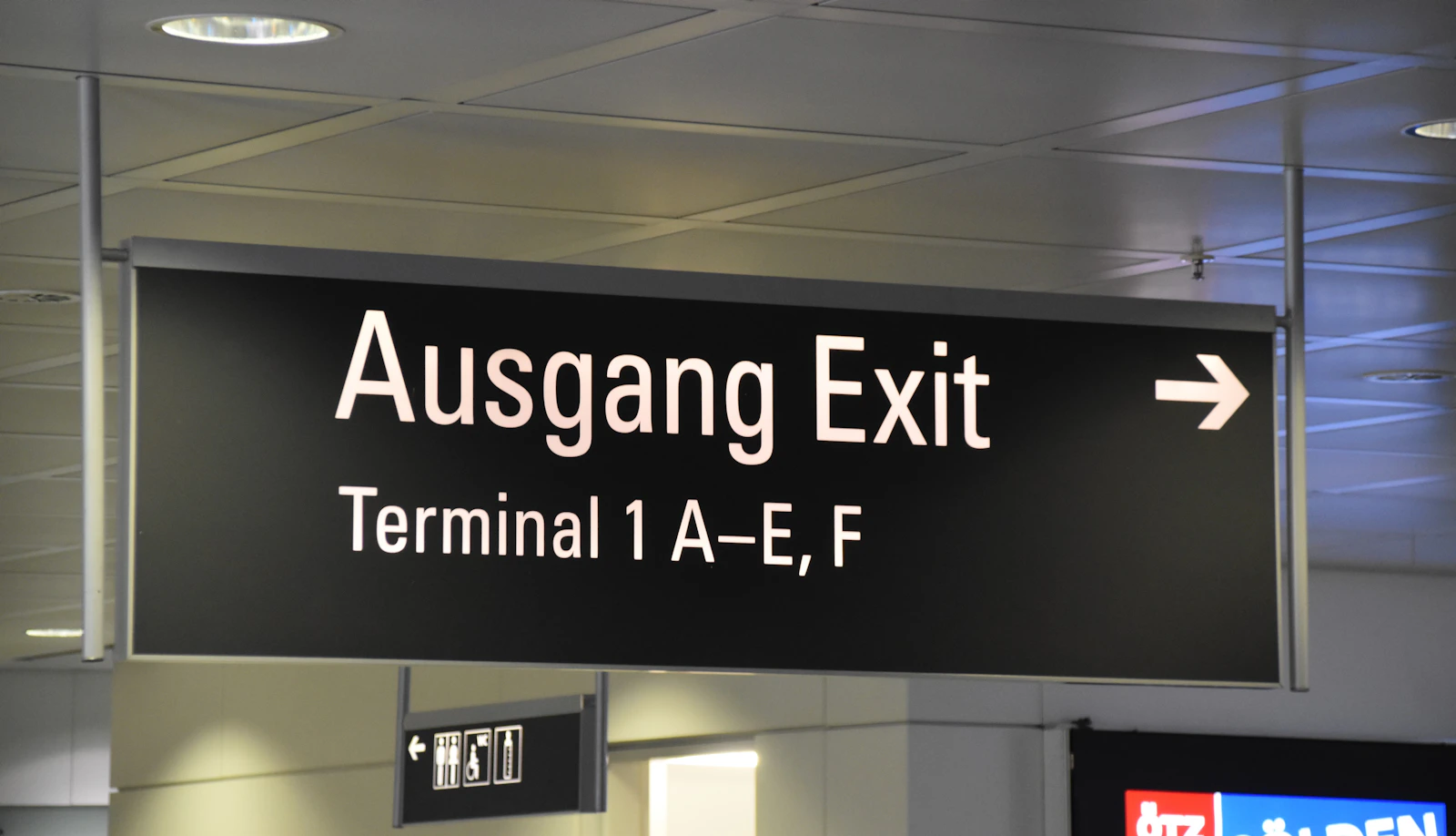 Overhead airport direction signs printed in several languages at once