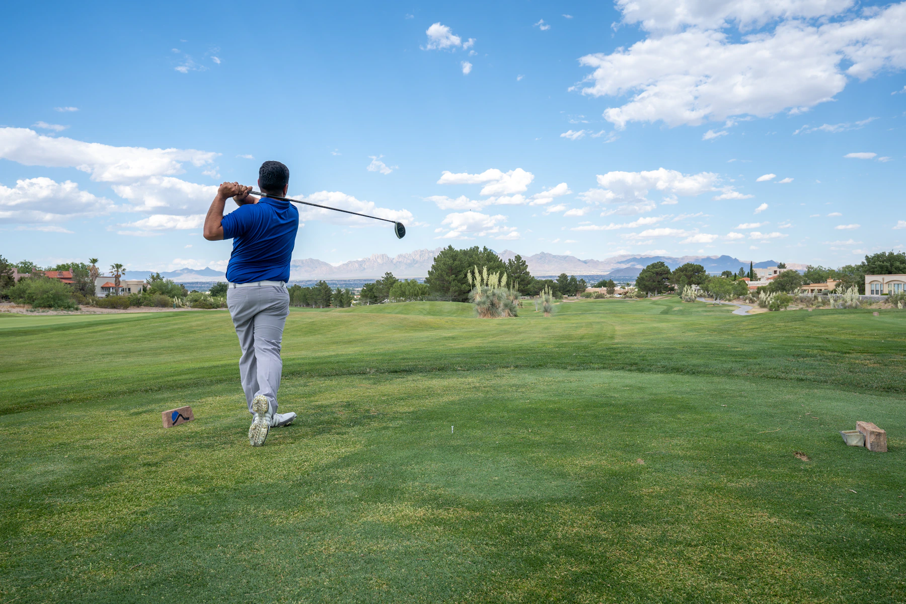Silver-haired man in his 60s finishing a golf drive on a manicured fairway