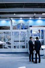 two men standing in front of glass wall