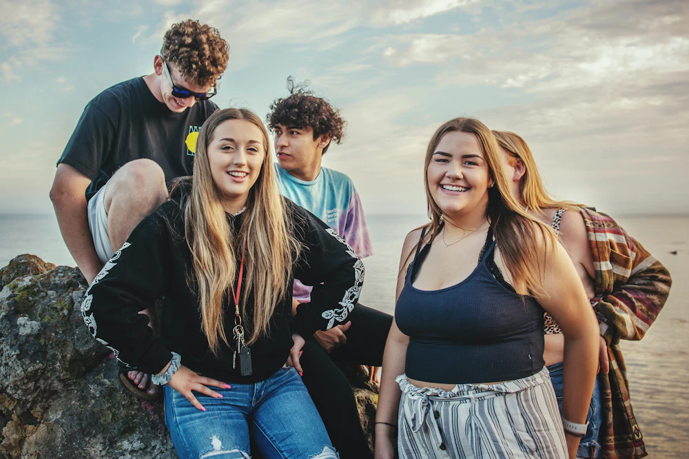 Grupo de adolescentes sobre unas rocas junto al agua, relajados y libres